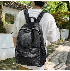 Outdoor back view of a woman wearing a vintage acid wash denim backpack in black