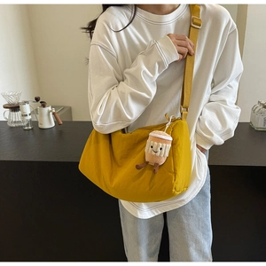 Detail of bright yellow nylon crescent crossbody bag with a cute coffee cup plush charm