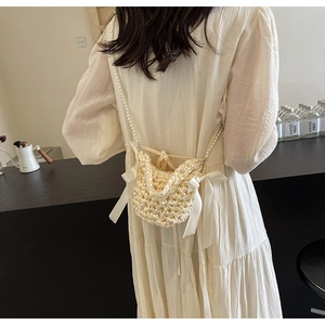 Detailed back view of a beige woven mini bag with pearl beads and ribbon bows