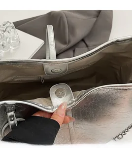 Close-up of tote bag showing metallic silver pleated texture and interior zipper pocket