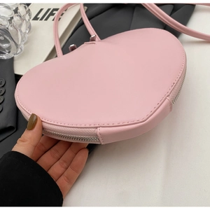 Dettaglio borsa a tracolla in pelle rosa a forma di cuore con cerniera argentata liscia