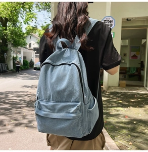 Outdoor shot showing the back view of a light blue denim backpack on a model's back