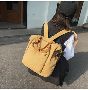 Detailed view of mustard yellow canvas backpack worn by model showing side buckle design