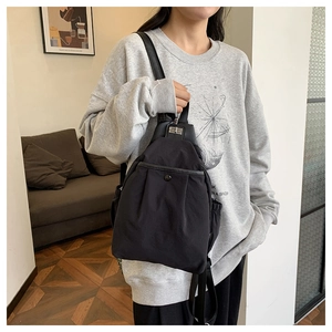 Détail du mini sac à dos en nylon noir avec fermoir rotatif et poche latérale à cordon