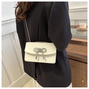 Detail of cream PU leather shoulder bag with a sparkling diamond butterfly bow ornament