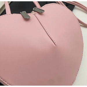 Dettaglio della borsa a cuore rosa in pelle PU con doppie cerniere e cuciture precise