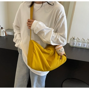 Detail of yellow canvas crossbody bag with coffee cup plush charm and crescent design