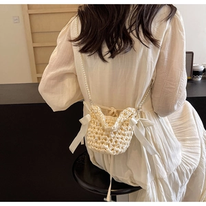 Detail of cream crochet crossbody bag with pearls and satin bows on pearl strap