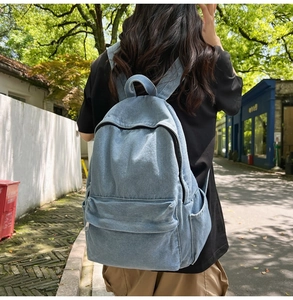 Outdoor shot of a light blue denim backpack with front pocket on a female model