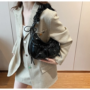 Close-up of black ruched PU leather handbag featuring a stylish decorative ribbon bow