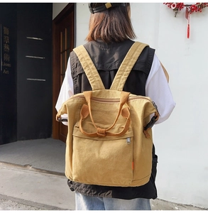 Ginger yellow canvas backpack with wide straps shown in an urban street setting