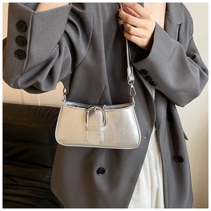 Detailed view of a silver metallic baguette bag with a stylish round metal buckle accent