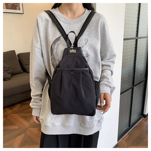 Détail d'un sac à dos en nylon noir avec fermoir rotatif argenté et poche frontale pratique