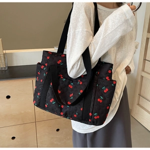 Quilted black tote bag with red cherry prints and functional side pockets for daily use