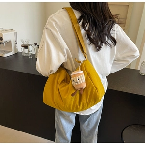 Close-up of ginger yellow half-moon canvas crossbody bag with coffee cup plush pendant