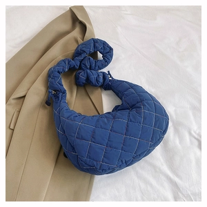 Blue quilted nylon crescent bag with ruffled strap on stylish white background