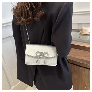 Close-up of elegant silver PU crossbody bag with sparkling rhinestone bow detail