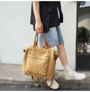 Detailed macro view of mustard yellow canvas tote bag with front zipper pocket