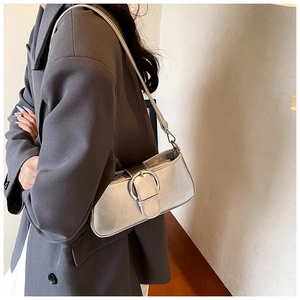 Detail of silver metallic PU leather underarm bag with large round buckle and strap