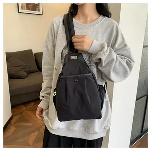 Détail du sac bandoulière en nylon noir avec boucle rotative en métal et poche avant
