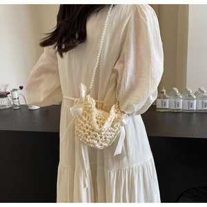 Detailed shot of cream pearl woven crossbody bag with silk bow and pearl strap