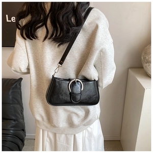 Detail of a black PU leather underarm bag featuring a large silver horseshoe buckle on strap