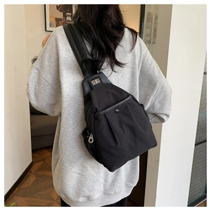 Détail du sac bandoulière en nylon noir avec boucle métallique et tissu plissé élégant