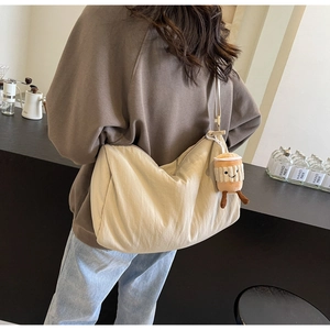 Detail of beige canvas crossbody bag featuring a plush coffee cup smiley charm decoration