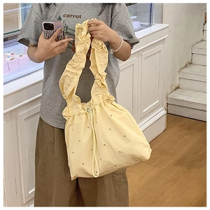 Detail of light yellow nylon handbag with ruffle shoulder strap and bead decorations