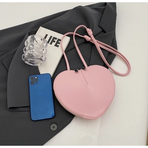 Dettaglio in piano di una borsa rosa a cuore con doppia zip e smartphone per scala dimensionale