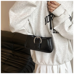 Detail of black faux leather crossbody bag with oily finish and silver horseshoe buckle