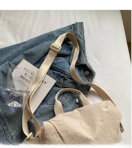 Detail showing the adjustable long shoulder strap on a beige lightweight nylon crossbody bag