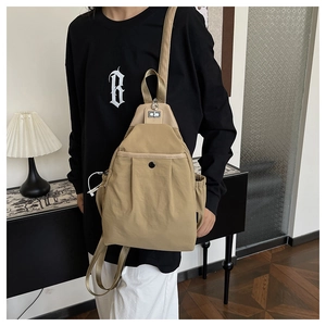 Détail du sac bandoulière en nylon kaki montrant la poche avant et la bandoulière ajustable