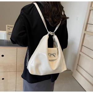 Detail of creamy white glossy PU backpack with silver metal bow and side chain decoration