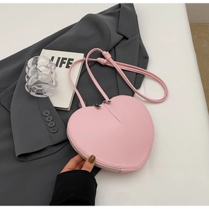 Dettaglio di una borsa a tracolla rosa a forma di cuore con finitura in pelle liscia