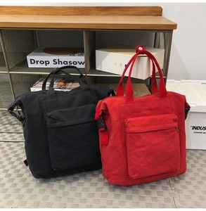 Detail of black and red canvas backpacks with front zipper pockets and top handles