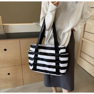 Detail view of the side pocket and wide black strap on striped tote bag