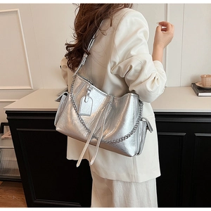 Silver metallic PU tote bag showing sleek glossy texture and chain strap on a model