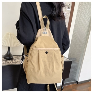 Détail du sac à dos en nylon beige porté par un mannequin dans un décor intérieur