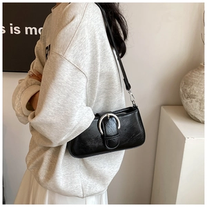 Detail of minimalist black PU leather crossbody bag with iconic silver circular metal buckle