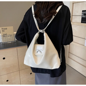 Close-up of cream PU leather underarm bag featuring a metallic bow and pleated design