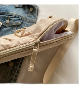 Detail view of cream nylon crossbody bag showing smooth zipper and woven drawstring strap