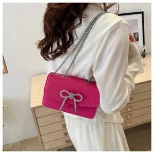 Detail of fuchsia PU leather crossbody bag featuring a sparkling rhinestone bow and chain