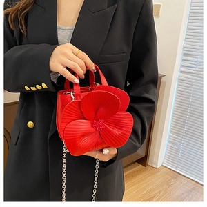 Detail view of red PU handbag featuring a 3D floral design and silver metal chain strap