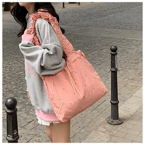 Side view of pink pleated shoulder tote bag with rhinestone studs and ruffle strap detail