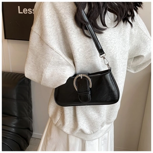Close-up of black PU leather baguette bag with a large silver buckle and zip closure