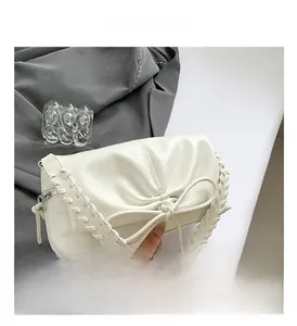 Detail of white PU shoulder bag featuring pleated design and leather bow with woven handle