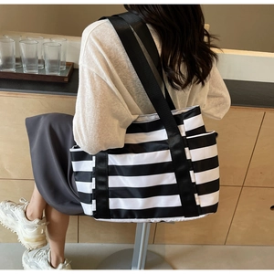 Close-up of black and white striped tote bag showing side pocket and nylon straps