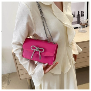 Detail of fuchsia PU leather shoulder bag with a sparkling rhinestone bow and chain