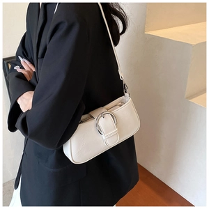 Close-up of white PU leather underarm bag with silver buckle worn on black blazer